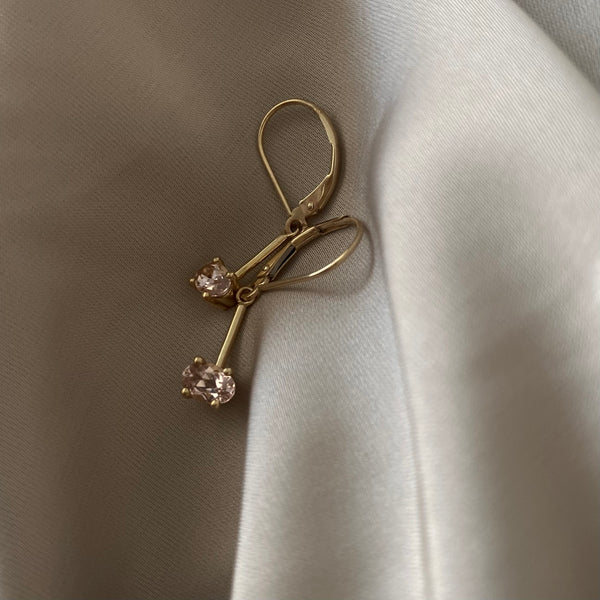 two leverback yellow gold earring with light pink morganite stones on a silk fabric