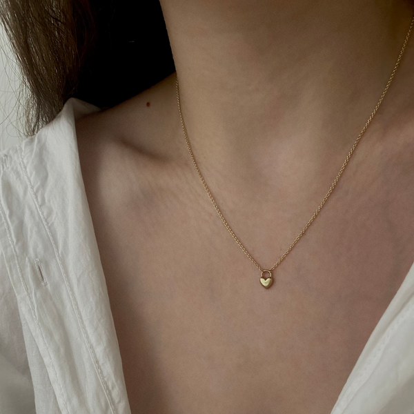 a woman wearing a gold heart necklace
