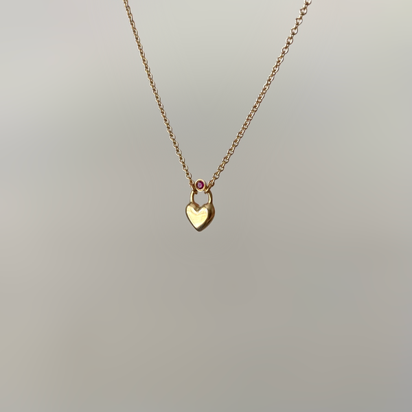 a heart necklace made of 14 karat gold, set with a ruby gemstone