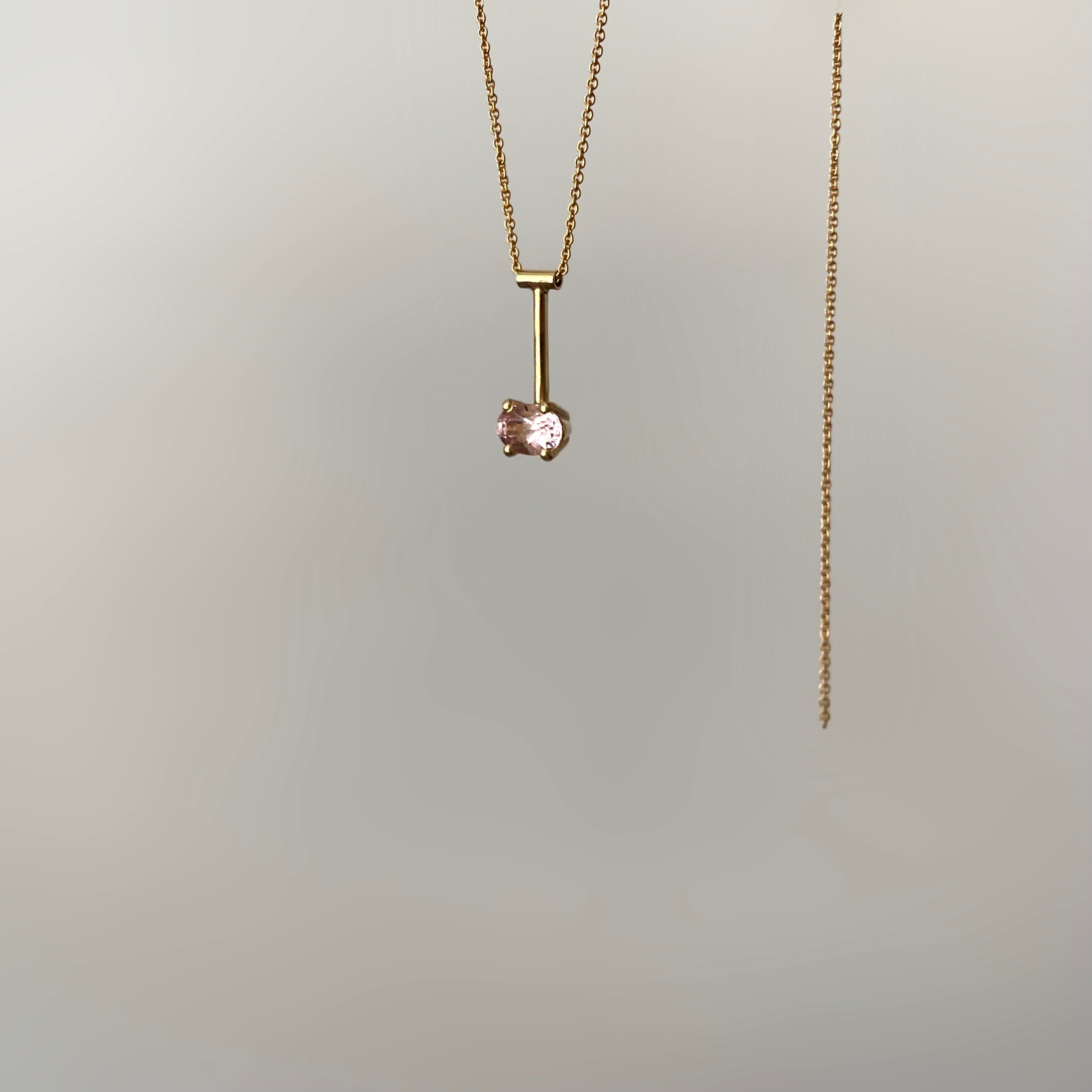 a 14 karat gold pendant with a pink morganite gemstone on white background