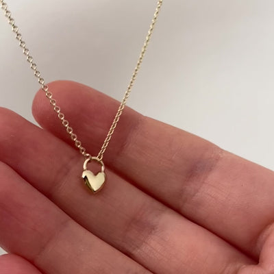 a well polished, shiny heart gold pendant hanging on a gold chain