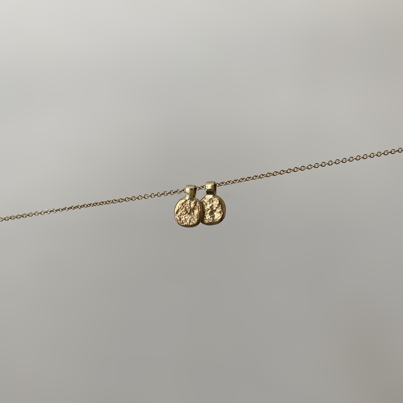 two 14 karat gold coin pendants on a dainty gold chain