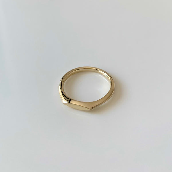 a marquise shaped signet gold ring on white background